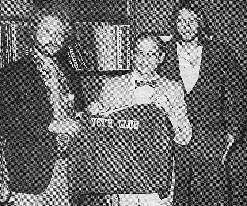 Mayo (left), president of the NMU Vets Club, and member Seppanen (right) present an honorary club jacket to former NMU President John X. Jamrich.