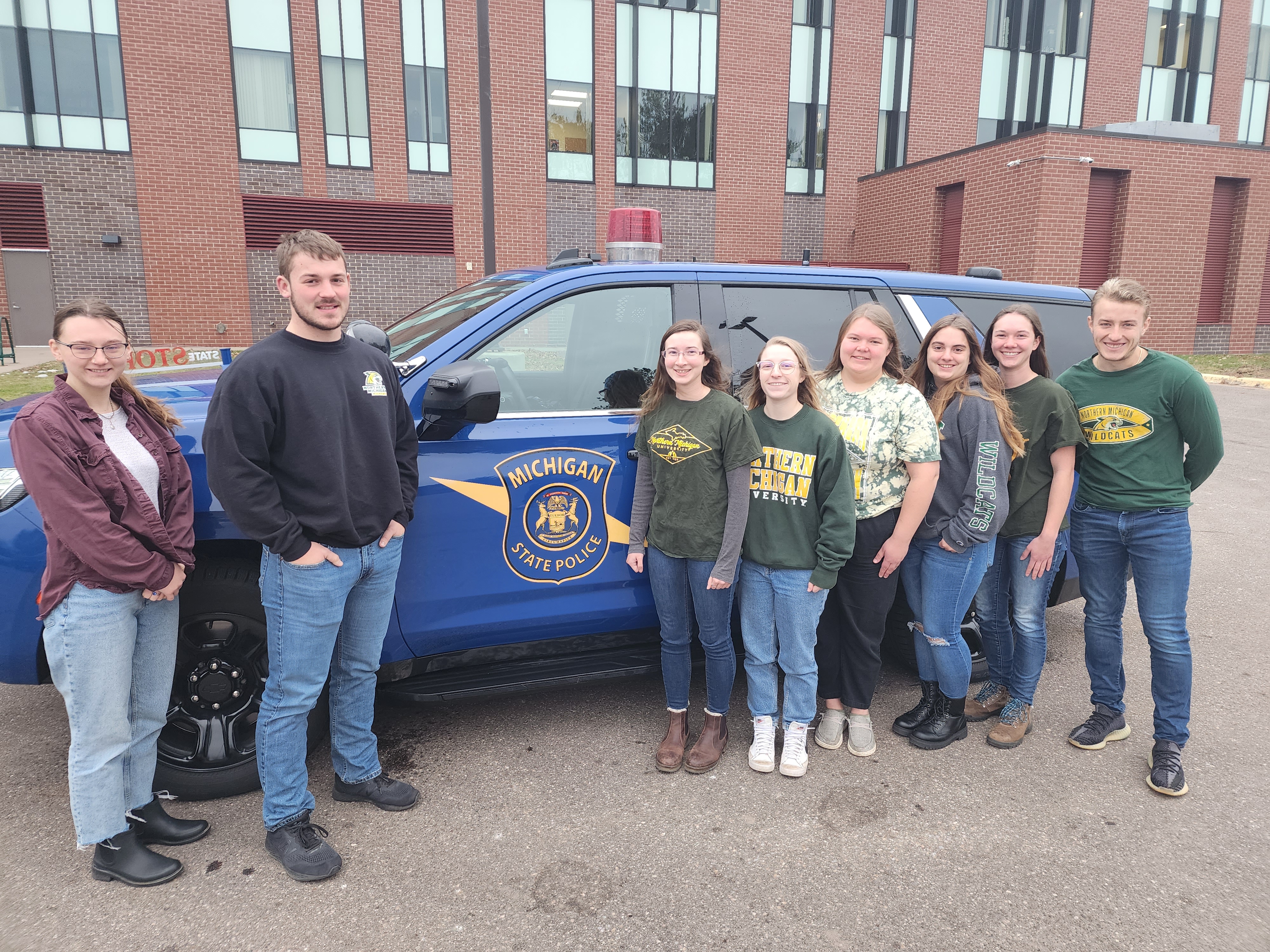 Cold case students in front of an MSP vehicle