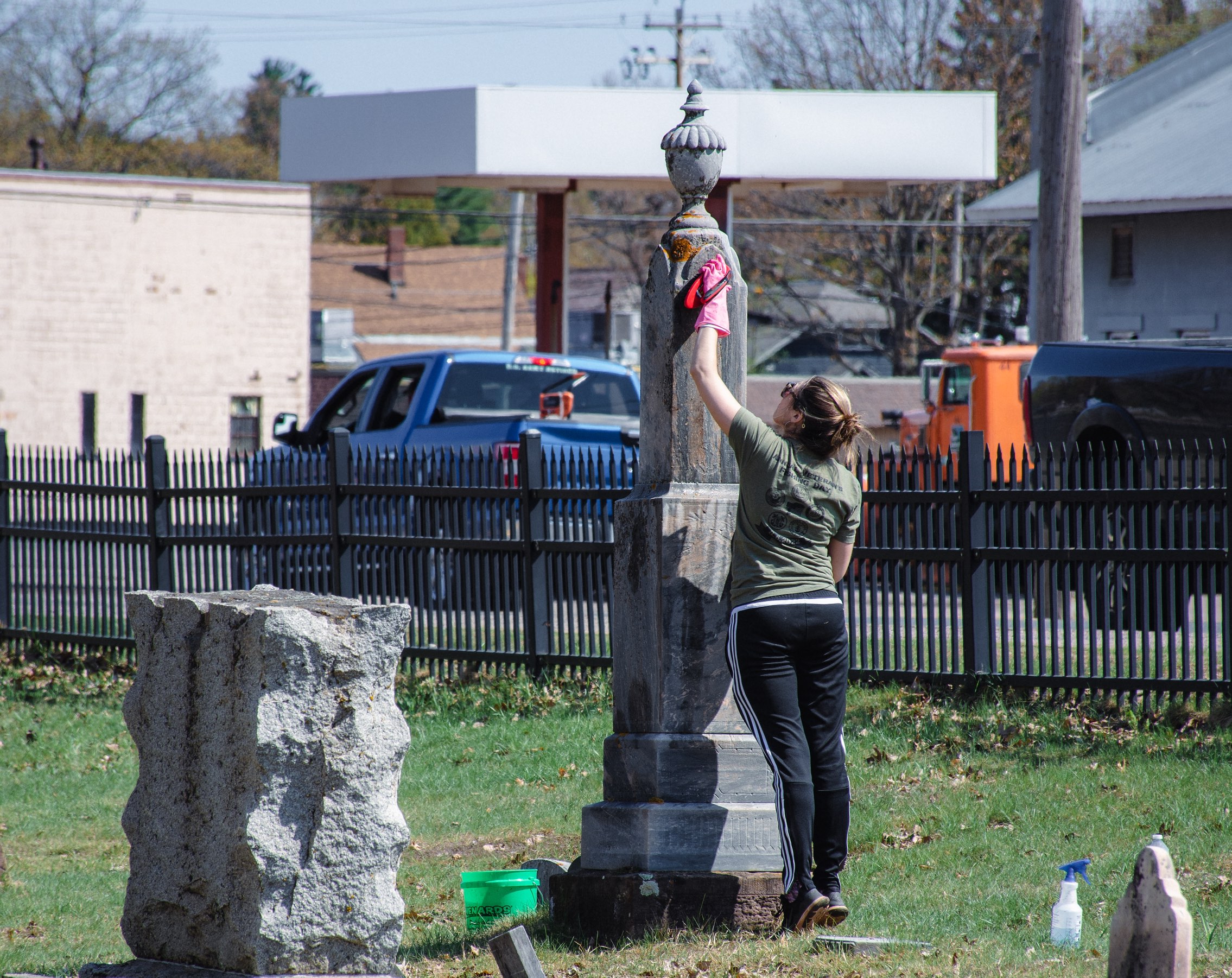 Volunteer reaches high to clean a tombstone