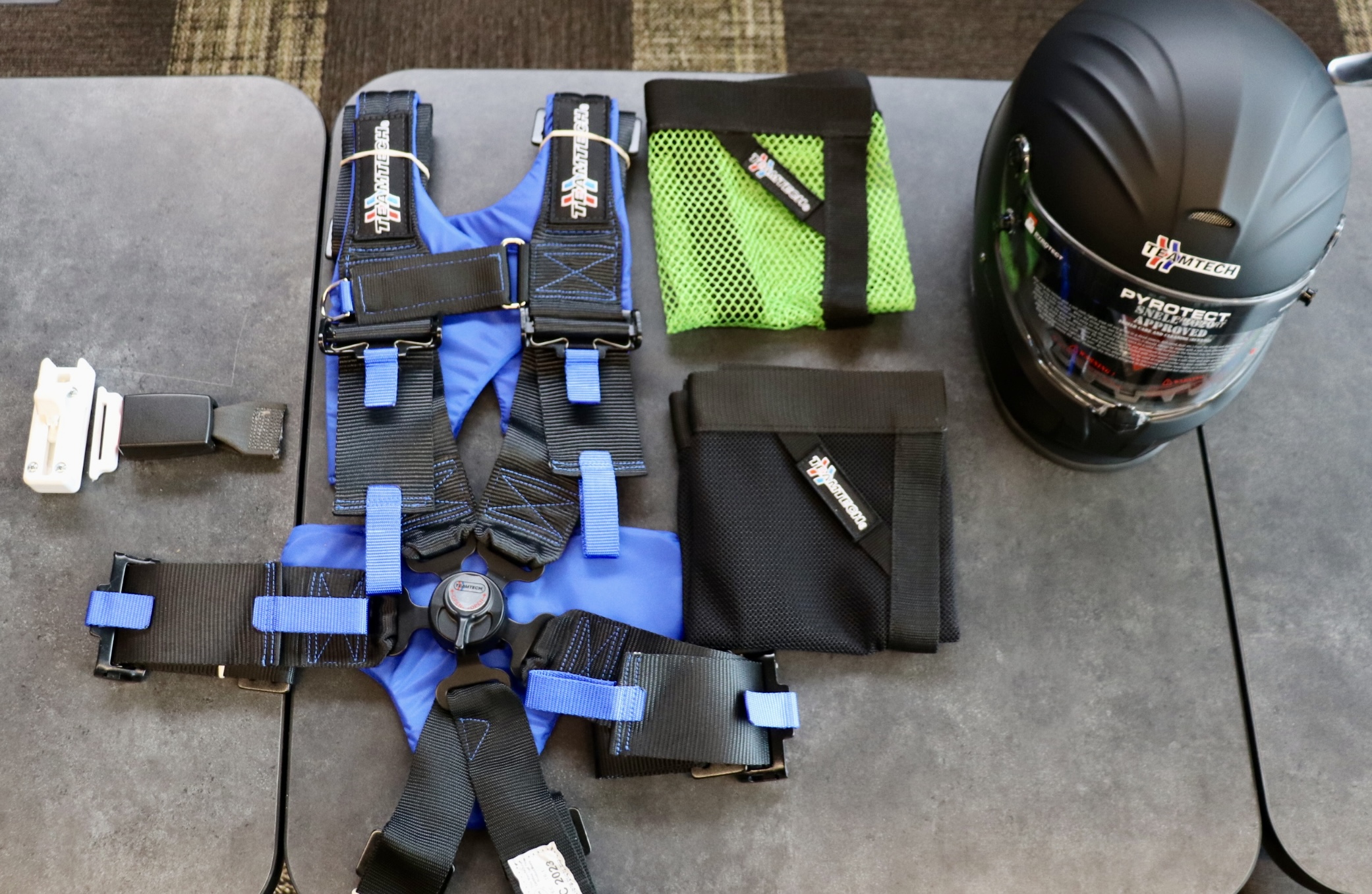 Some of Tucker's TEAMTECH motorsports products (from left): seat belt cutter prototype, harness with buckle, window nets and helmet.