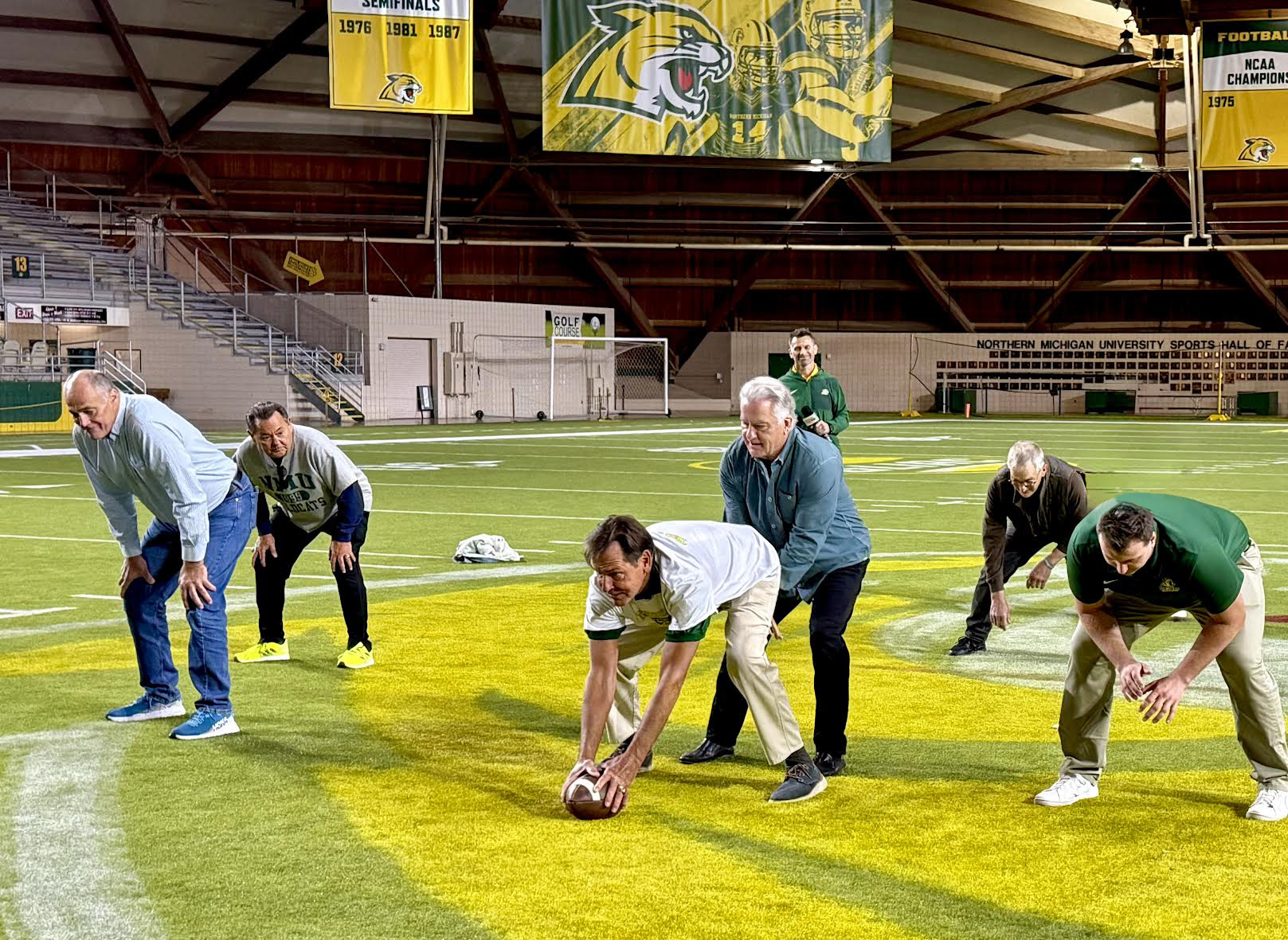 From left: 1975 players Jack Hirn, Bob Tuma, Dan Stencil, Steve Mariucci and Kurt Albrecht in the backfield ran a few plays with a current Wildcat for a TV segment previewing the reunion.