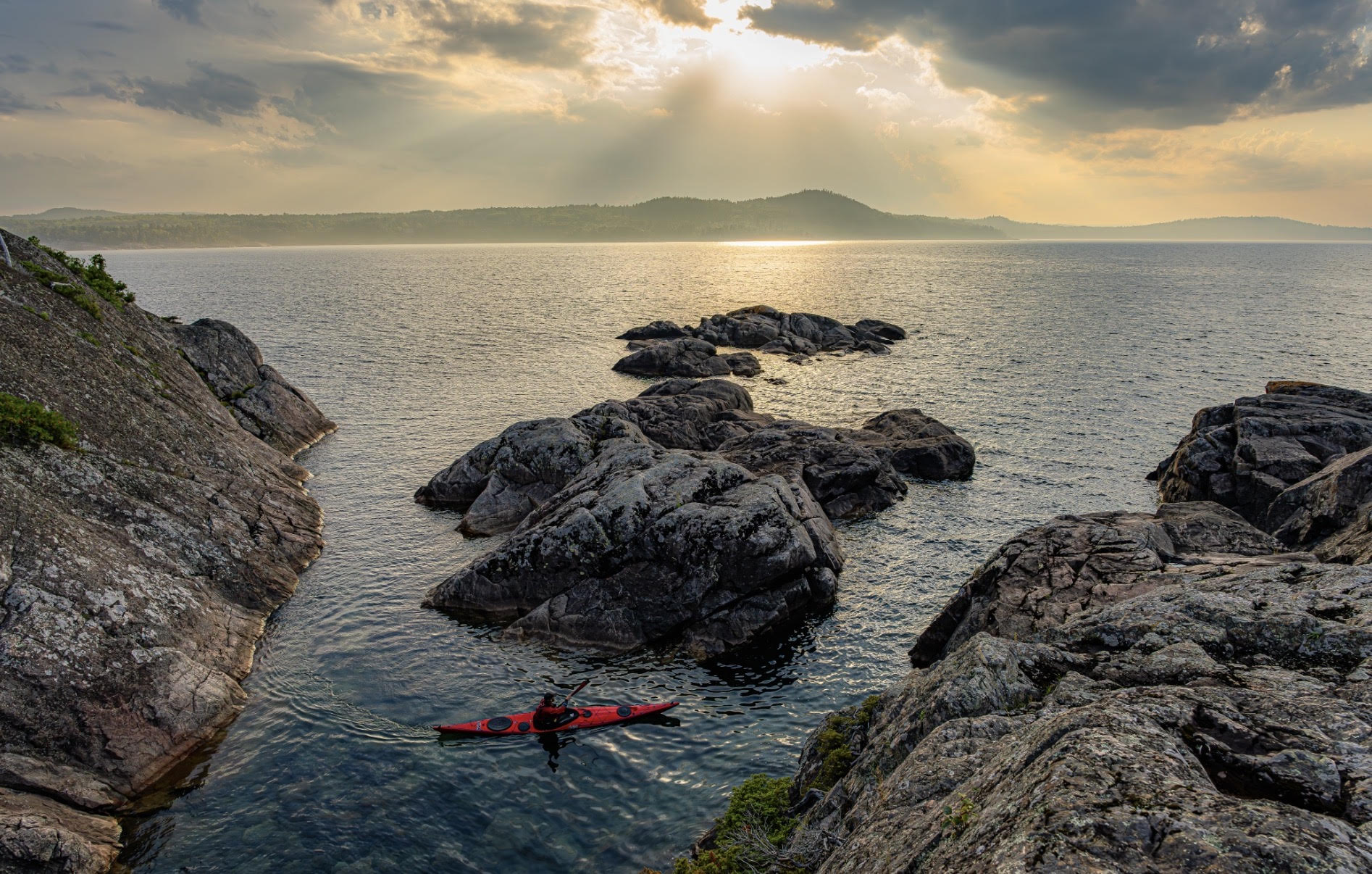 Lasak paddling through large rocks protruding from Lake Superior