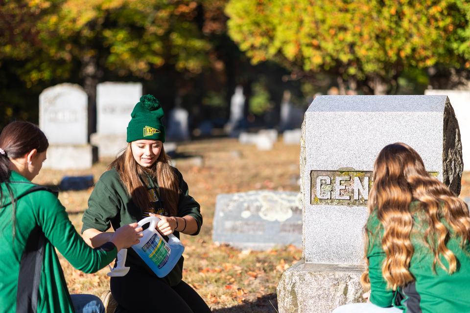 NMU ROTC cadet Victoria Sloan, a freshman, cleans a gravestone.