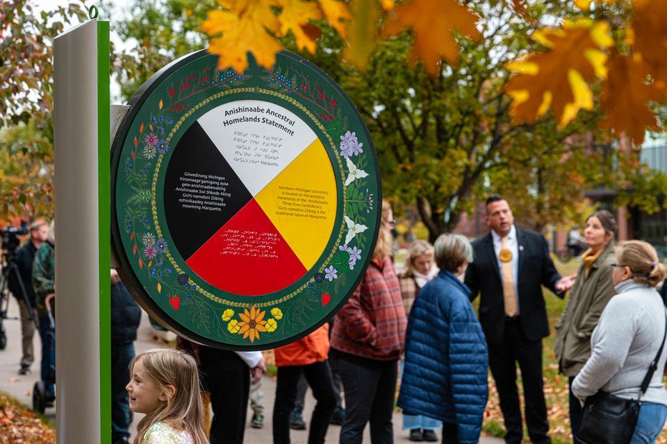 A crowd gathered around the territory acknowledgment sign on campus.