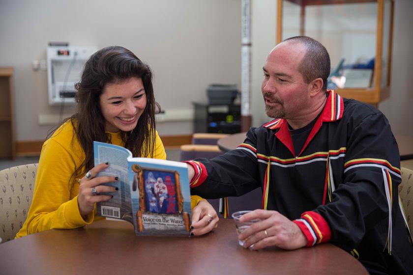 File photo of Reinhardt (right) showing a student a book on Great Lakes Native Americans.