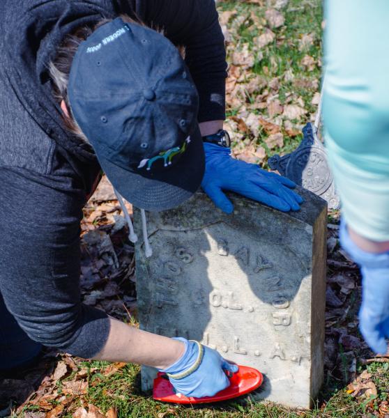 Volunteer scrubs a tombstone