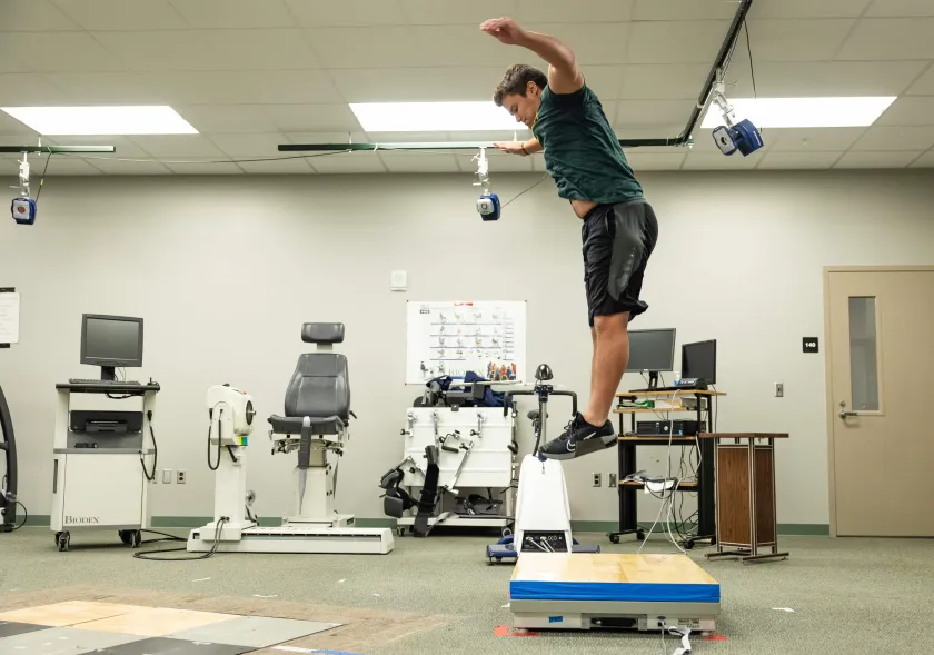 A student jumping and landing on the flooring sample.