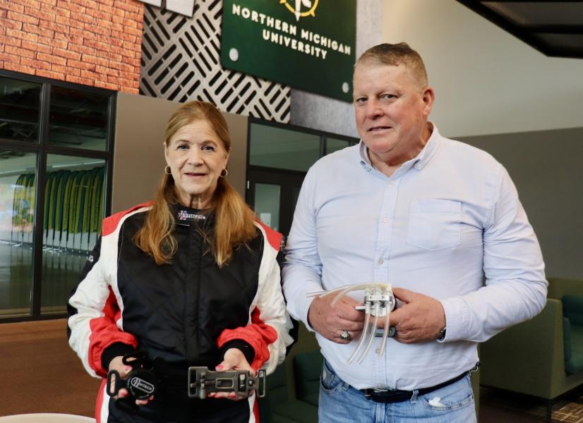 Curt Tucker holds a prototype of the multi-function seat belt buckle being reviewed by NASA. His wife, Korina, models a TEAMTECH racing suit and holds in her left hand the self-tightening over center (STOC) seat belt buckle being reviewed for use in NASCAR races.