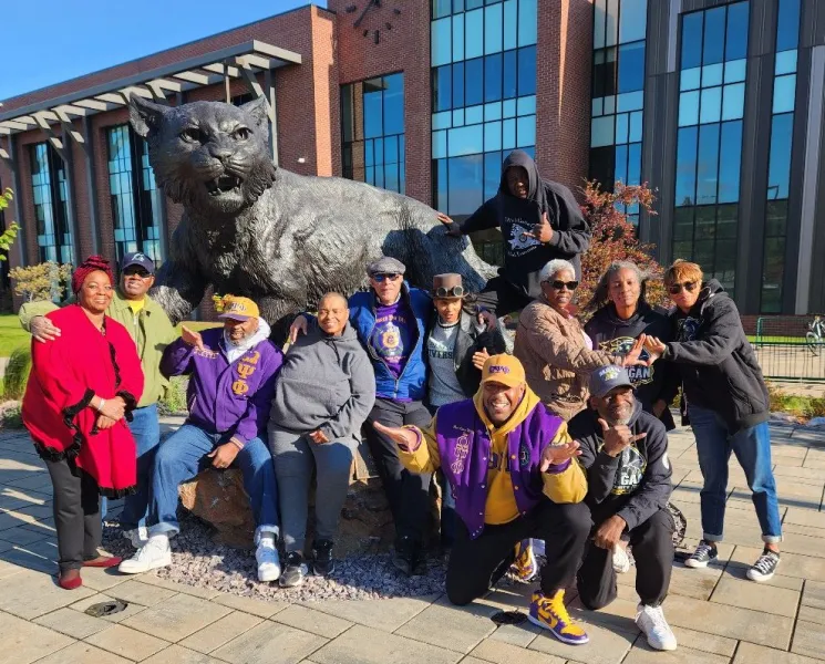 Reunion attendees pose for a photo in front of the Wildcat statue.