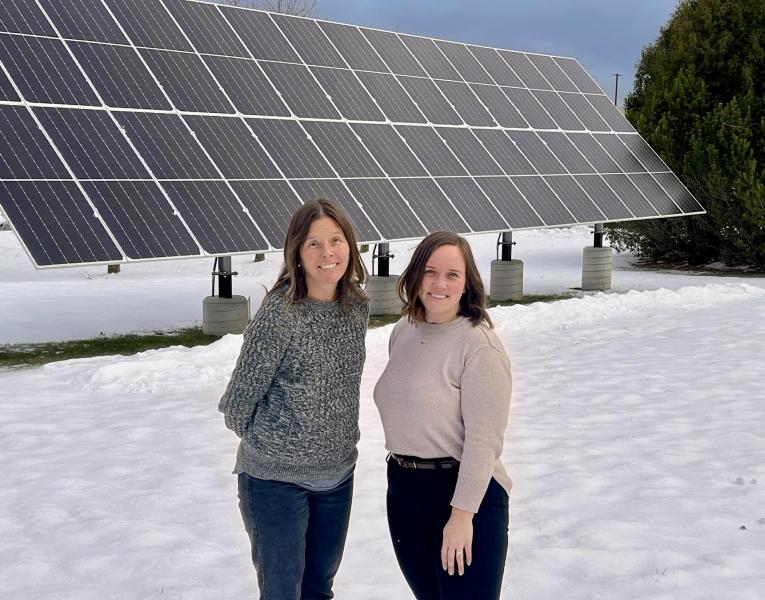 Jes Thompson (left) and Anna Solberg in front of the solar array on campus.