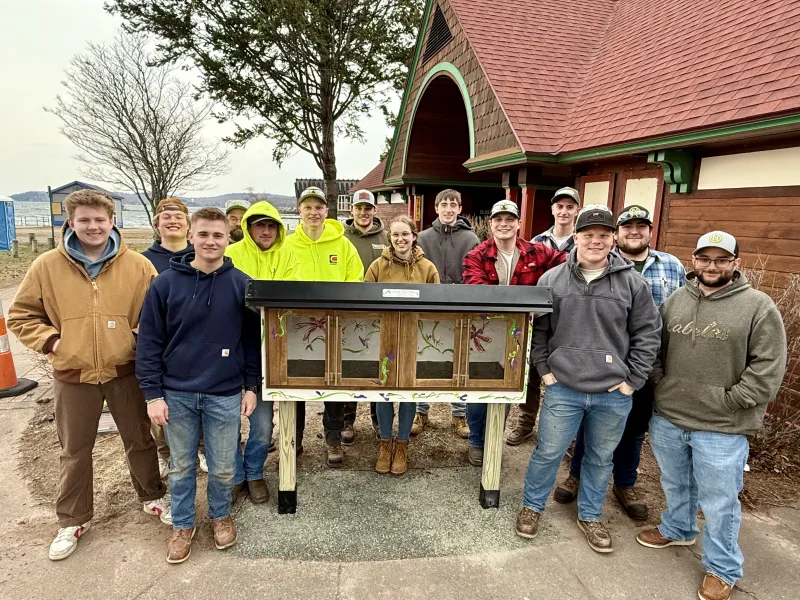 Northern Michigan Constructors surround the free library they built and installed.