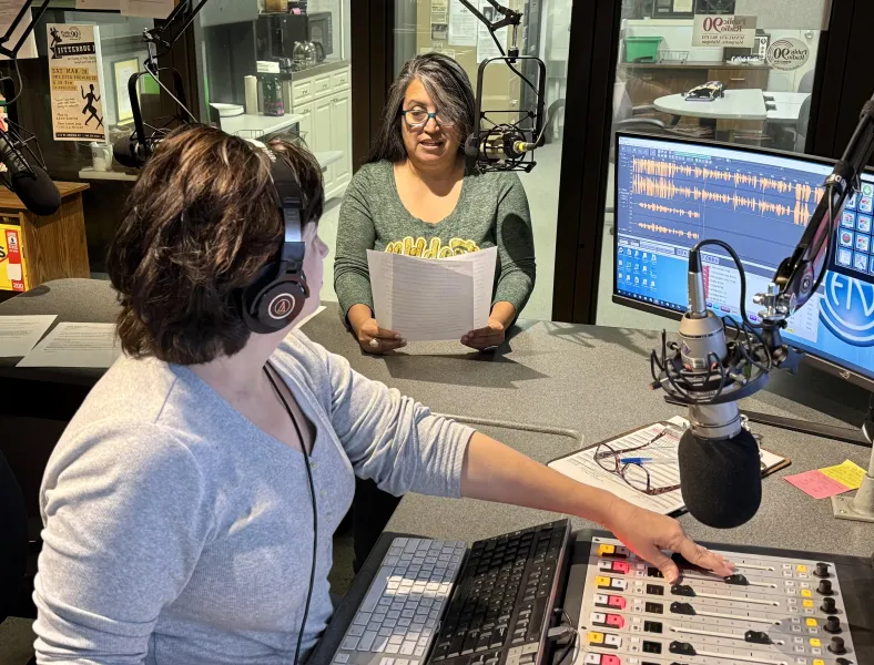 Lindala (background) narrates a vignette while Walton operates the board.