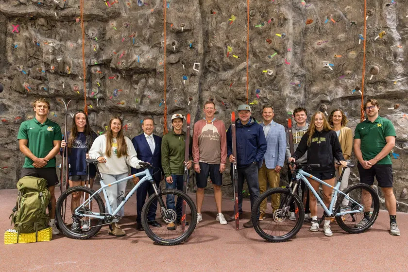 NMU Interim President Gavin Leach, fourth from left, and Blackrocks' Steve Farr (’09 BS, ’12 MBA), David Manson and Andy Langlois ('95 BS), center, are pictured with NMU students and staff showing some of the bikes and skis purchased through the partnership.