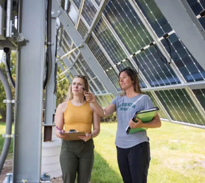 File photo of Jes Thompson (right) with a student near a solar array on NMU's campus.