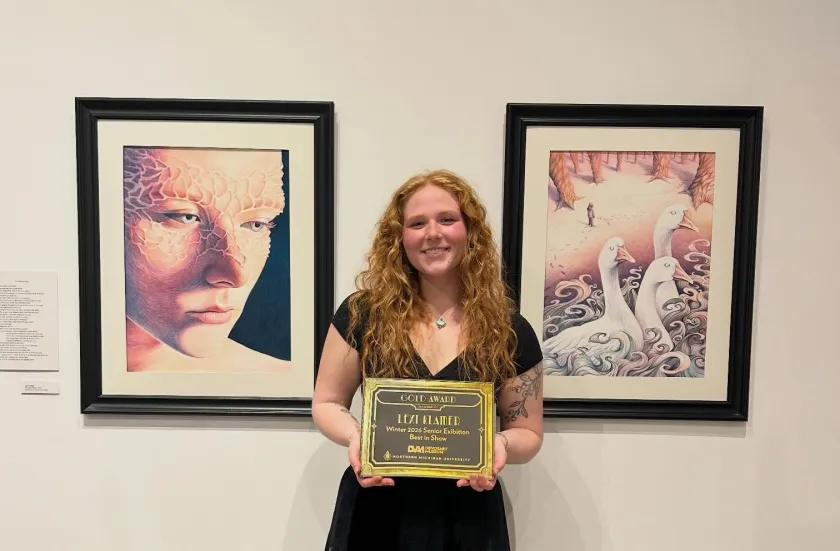Klamer with her gold award certificate in front of two pieces she created for the NMU School of Art & Design Senior Exhibition.