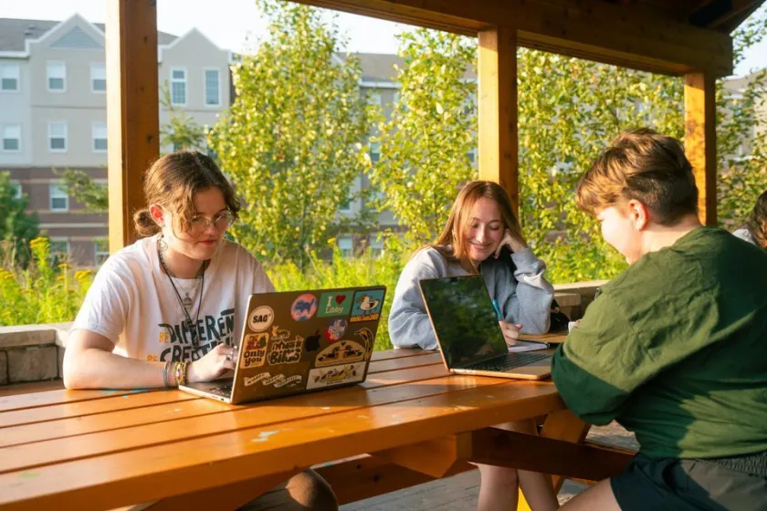 Students seated at picnic table outside studying