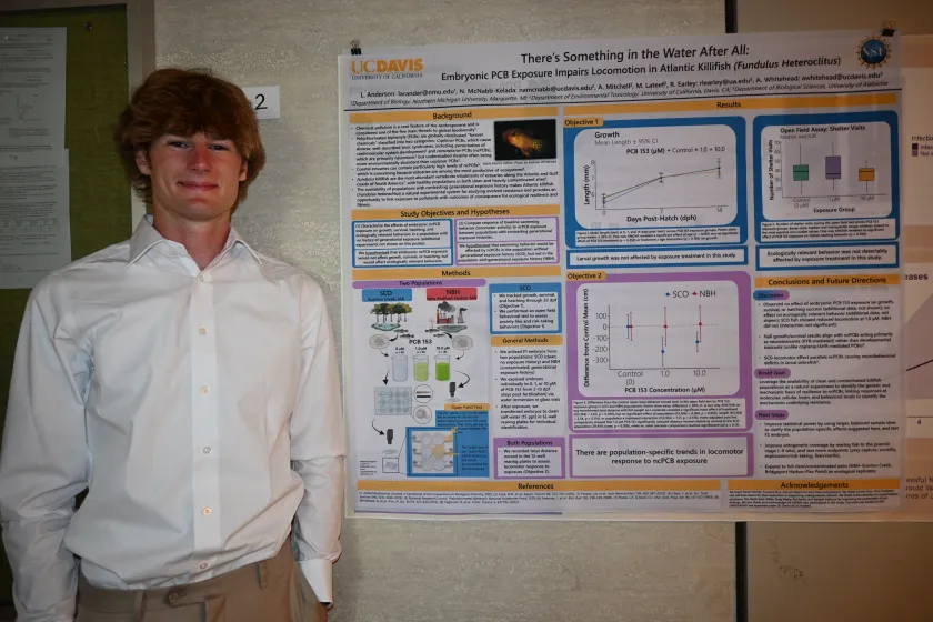 Lars Anderson stands next a presentation on his research.