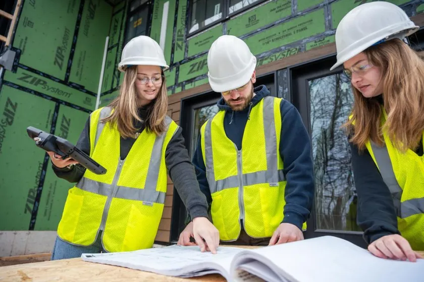NMU Construction Management students look at blueprints outside.