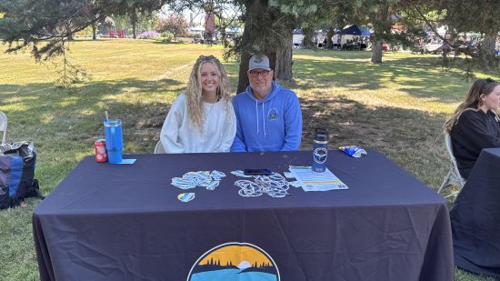 Kaysie Bakke and Alan Cook seated at their booth at NMU's Fall Fest