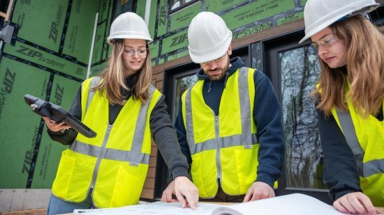 NMU Construction Management students look at blueprints outside.