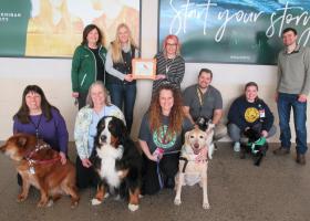 Pictured are: (front row from left) Pet Partners Ann Dausey, Kelly December and Tanya Savage with their dogs; and (back row from left) health fair committee member Sharon Carey, Health Promotion Society President Haley Anderson, Pet Partner Kim Benson-Custard (holding the award), Rick Custard, Bethany Rudness, and health fair committee member Matt Kilgas. 