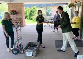 Katie and Allie deliver computers to Norlite administrator Wayne Johnson, with other staff looking on.