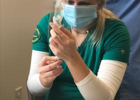 A nursing student prepares to administer a vaccine.