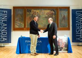 FinnU President Philip Johnson (left) and NMU President Fritz Erickson shake hands