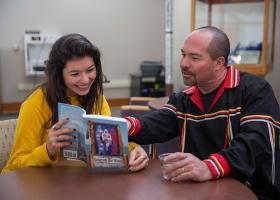 File photo of Reinhardt (right) showing a student a book on Great Lakes Native Americans.