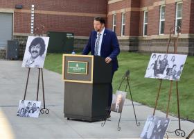 Jeff Korpi speaks at the dedication, surrounded by photos of Holm.