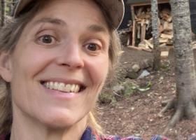 Mittlefehldt in front of her wood pile at camp.