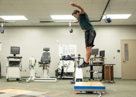 A student jumping and landing on the flooring sample.