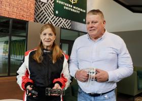 Curt Tucker holds a prototype of the multi-function seat belt buckle being reviewed by NASA. His wife, Korina, models a TEAMTECH racing suit and holds in her left hand the self-tightening over center (STOC) seat belt buckle being reviewed for use in NASCAR races.