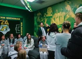 Sandoval (center) points to the updated mural featuring photos from last year's GLIAC Championship during an open house for the renovated locker room earlier this season.