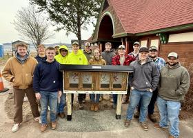 Northern Michigan Constructors surround the free library they built and installed.