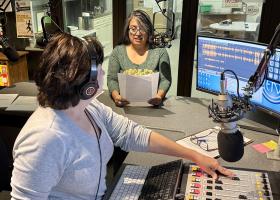 Lindala (background) narrates a vignette while Walton operates the board.