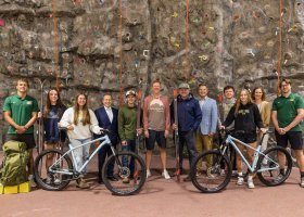 NMU Interim President Gavin Leach, fourth from left, and Blackrocks' Steve Farr (’09 BS, ’12 MBA), David Manson and Andy Langlois ('95 BS), center, are pictured with NMU students and staff showing some of the bikes and skis purchased through the partnership.