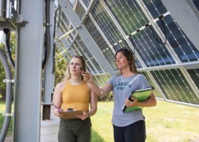 File photo of Jes Thompson (right) with a student near a solar array on NMU's campus.