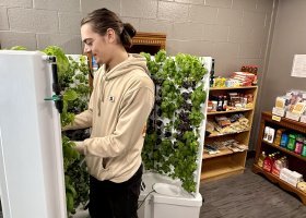 Student Raymond Greimel attends to the greens growing in a hydroponic unit in the NMU Food Pantry satellite location in the Jacobetti Complex