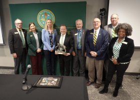 Gavin Leach (center, with Wildcat statue) was honored for his leadership of NMU the past six months by Trustees (from left): Steve Young, Lisa Fittante, Missie Holmquist, Steve Lindberg, Greg Toutant, Greg Seppanen and Venus Joy Brown.