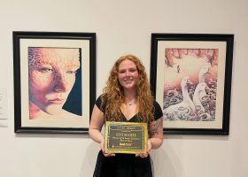 Klamer with her gold award certificate in front of two pieces she created for the NMU School of Art & Design Senior Exhibition.