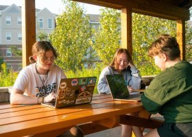 Students seated at picnic table outside studying