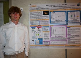 Lars Anderson stands next a presentation on his research.