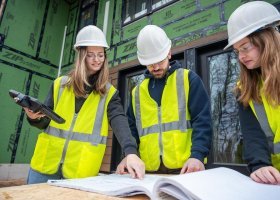 NMU Construction Management students look at blueprints outside.