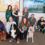 Pictured are: (front row from left) Pet Partners Ann Dausey, Kelly December and Tanya Savage with their dogs; and (back row from left) health fair committee member Sharon Carey, Health Promotion Society President Haley Anderson, Pet Partner Kim Benson-Custard (holding the award), Rick Custard, Bethany Rudness, and health fair committee member Matt Kilgas. 
