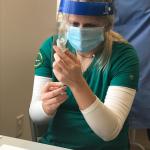 A nursing student prepares to administer a vaccine.