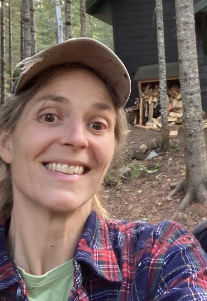 Mittlefehldt in front of her wood pile at camp.